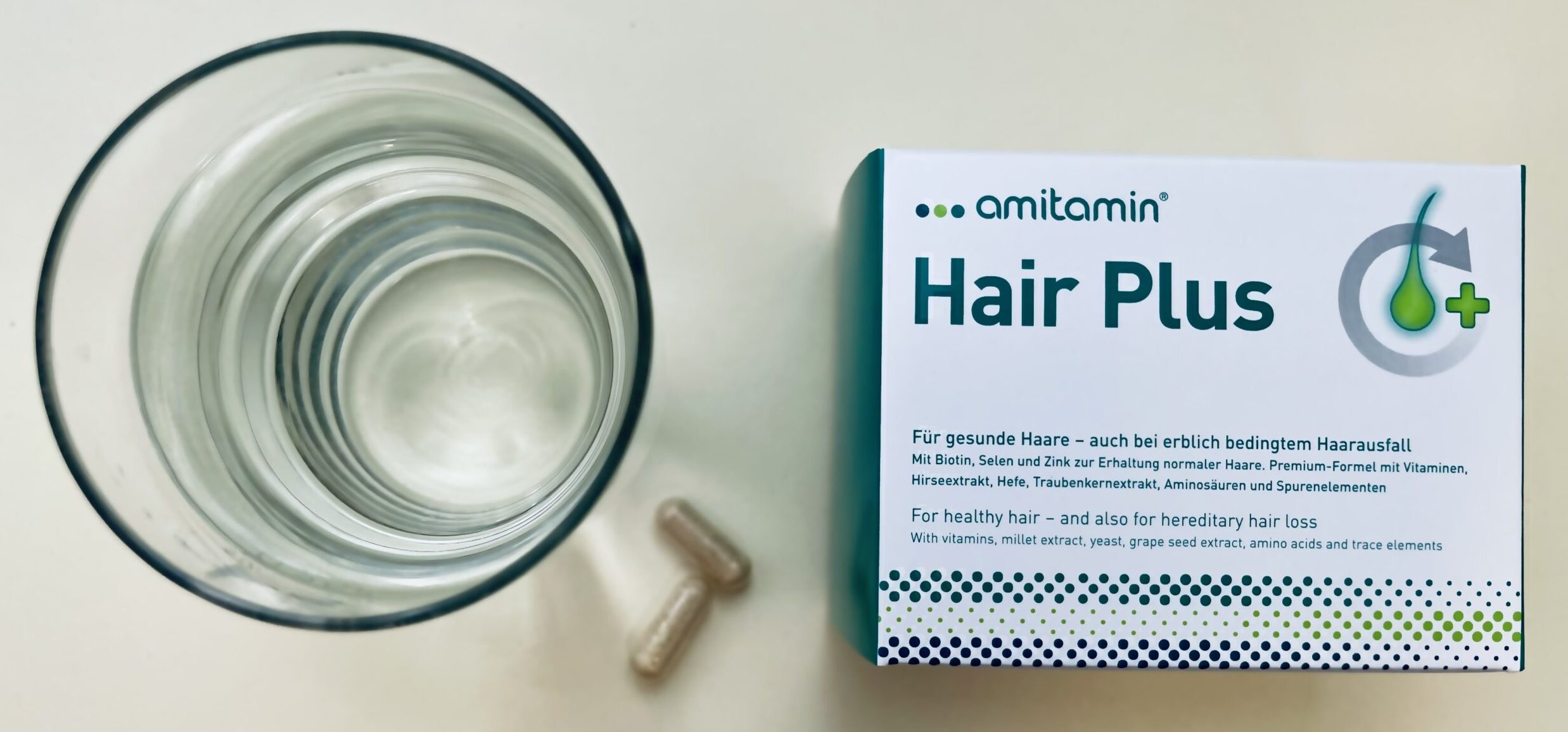 amitamin Hair Plus mit zwei Kapseln und einem Glas Wasser zur täglichen Einnahme